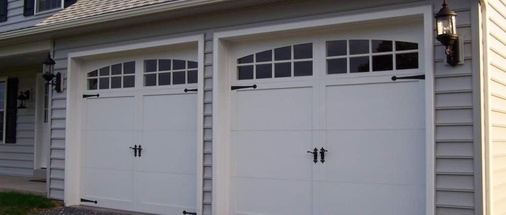 Double white colored garage door with outdoor post lamp